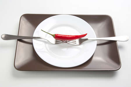 Red hot pepper with fork close-up on plate. Healthy vegetable food and vitaminsの写真素材