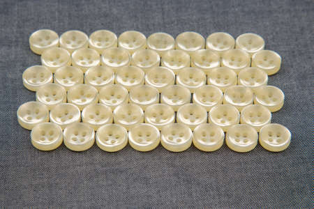 Plastic shiny buttons for clothes on a fabric background. Fashion and clothing. Factory industry.