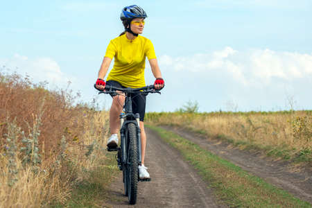 beautiful and happy girl cyclist rides a bicycle on the road in nature. Healthy lifestyle and...