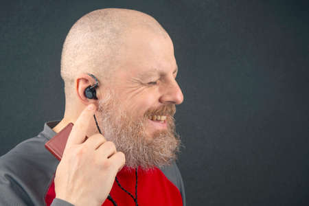 bearded man enjoys listening to his favorite music through an audio player in small headphones....