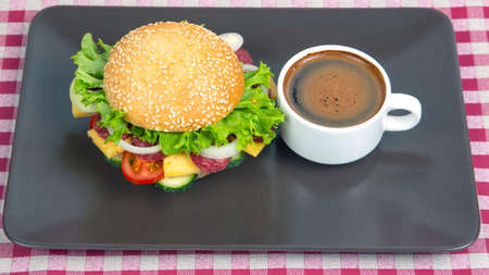Hamburger with vegetables and sausage and coffee on a gray background. Fast food and breakfast. Calories and diet.の写真素材