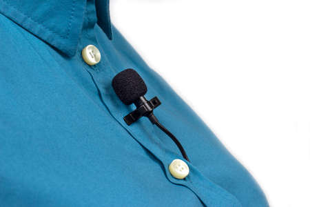 The lavalier microphone is secured with a clip on a blue women's shirt close-up. Audio recording of the sound of the voice on a condenser microphone.の写真素材
