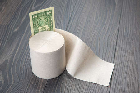 toilet paper with dollar bill on wooden backgroundの写真素材