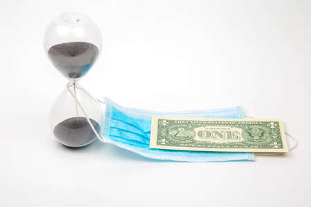 hourglass, dollar and medical mask on a white background. time and protection from the virus....