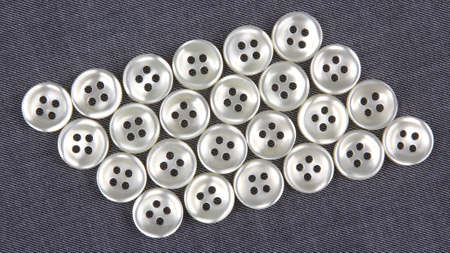 Plastic shiny buttons for clothes on a fabric background. Fashion and clothing. Factory industry