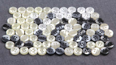 Plastic shiny buttons for clothes on a fabric background. Fashion and clothing. Factory industry
