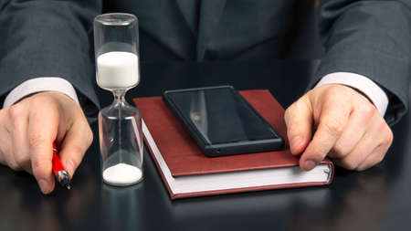 business man in the office is working on the background of the hourglass. business and successful...