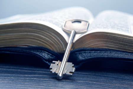 the key lies on an open bible book. metaphor for discovering wisdom through the study of religious literatureの写真素材