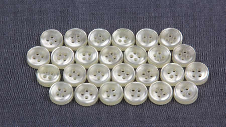 Plastic shiny buttons for clothes on a fabric background. Fashion and clothing. Factory industry