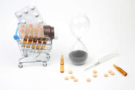 pills, ampoules and syringe for injection, money dollars and hourglass on a white background....