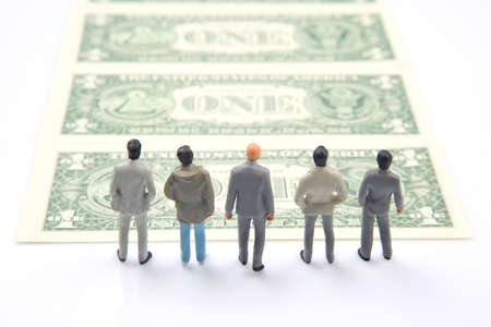 miniature people. different businessman stands near dollar money. investments and earnings for workの写真素材