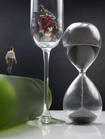 miniature people. man addicted to alcohol is walking on a bottle against the background of a glass...
