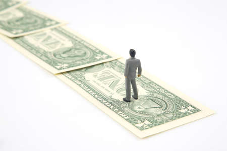 miniature people. businessman stands near dollar money. investments and earnings for workの写真素材