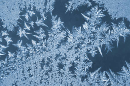 frosty patterns on the window glass closeup. natural textures and backgrounds. ice patterns on...