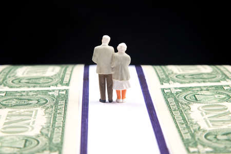Miniature people. Elderly people, retirees, walk the road of life along the money towards the end of their lives. Pension and security in old age.の写真素材