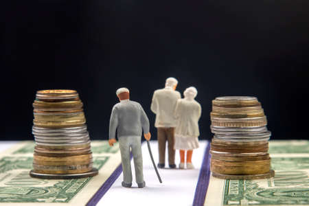 Miniature people. Elderly people, retirees, walk the road of life along the money towards the end of their lives. Pension and security in old age.の写真素材
