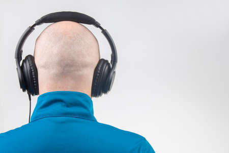 part of the back of the head of a man with headphones in relaxation listening to music on a light background. copy spaceの写真素材