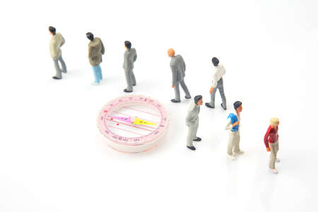 miniature people. different people are standing near the compass. finding direction in life