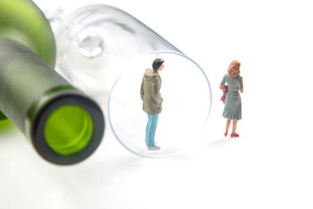 miniature people. man addicted to alcohol on the background of a bottle of wine and a glass and a broken family. the problem of alcoholism in societyの写真素材