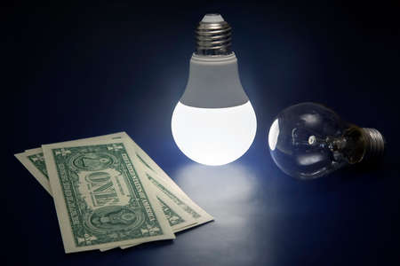 Glowing LED lamp and dollar bill on a dark background. Business and savings. Modern technology and electricityの写真素材