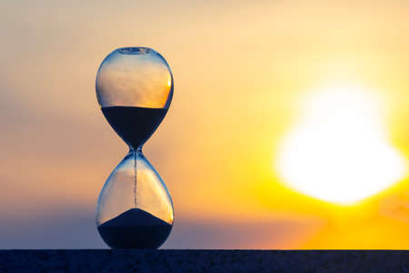Hourglass counts the length of time against the background of the evening sunの写真素材