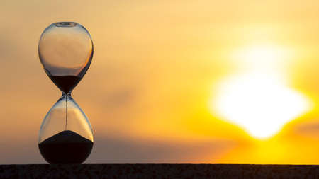 Hourglass counts the length of time against the background of the evening sunの写真素材