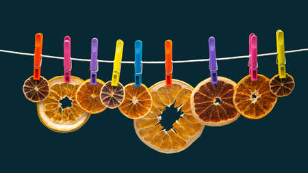 dried pieces of different citrus fruits hang on colored clothespinsの写真素材