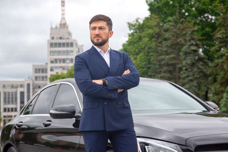 successful businessman is standing near his prestigious carの写真素材