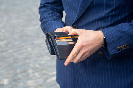 businessman in a suit opens his business leather wallet close-up. Finance and prosperity in the economyの写真素材