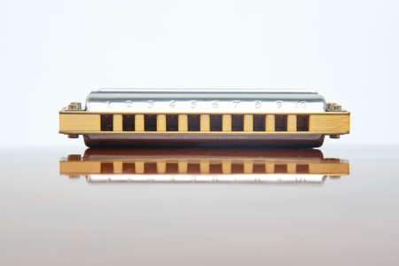The harmonica lies on a mirrored surface. Classical musical wind instrument.の写真素材