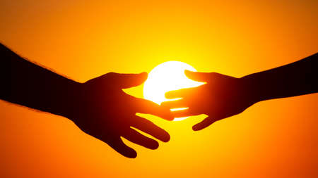 silhouette of male and female hands on the background of the setting sun. concept of communication...