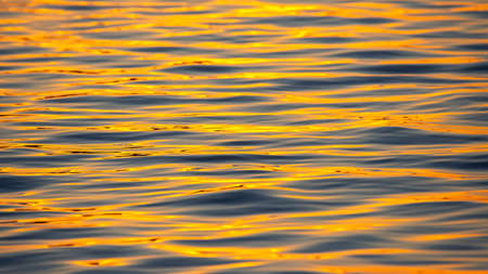 Reflection of the setting sun in a wave of water. Natural background texture