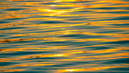 Reflection of the setting sun in a wave of water. Natural background textureの写真素材