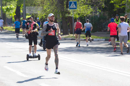 Kharkiv, Ukraine - May 16, 2021: Kharkiv Half Marathon. The athlete actively participates in the marathon, running a distance along a city streetのeditorial素材