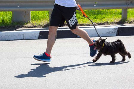 Kharkiv, Ukraine - May 16, 2021: Kharkiv Half Marathon. runner with his beloved dog participating in a marathon, running a distance along a city streetのeditorial素材
