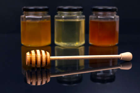 Hexagonal jars with different types and colors of fresh flower honey and a honey spoon. vitamin food...