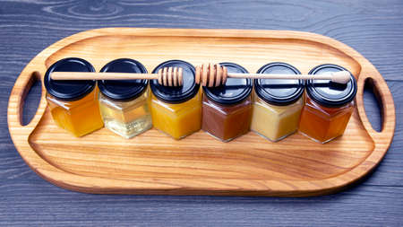 Hexagonal jars with different types and colors of fresh flower honey and a honey spoon. vitamin food for health and lifeの写真素材