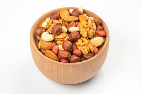 assortment of nuts in a wooden plate on a white background. vitamin organic food