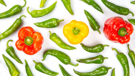 green hot peppers and red and yellow bell peppers on a white background. vitamin vegetables for...