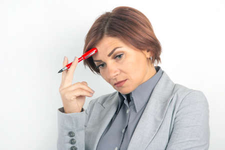 Beautiful young business girl with a red pen in hand on a white background