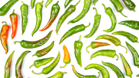 green hot peppers evenly spread on a white background. vitamin vegetables for health
