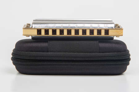 Harmonica in a case on a white background. Classical musical wind instrument.