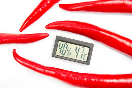 digital thermometer for measuring air temperature and humidity on the background of red hot peppers....