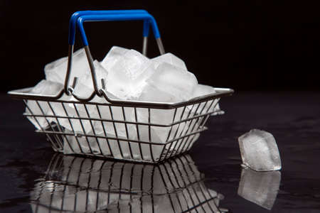 frozen ice cubes in a grocery basket on a dark backgroundの写真素材