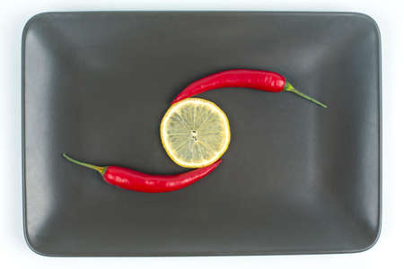 Red hot pepper with lemon on a gray plate. Healthy vegetable food and vitaminsの写真素材