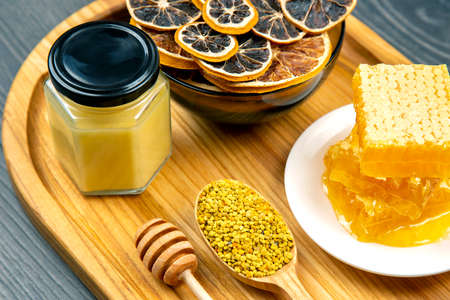 assortment of nuts and assorted dried citrus fruits and fresh floral honeycomb honey and pollen on kitchen wooden board. useful vitamin food for the human bodyの写真素材