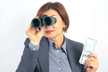 Successful business woman with binoculars and dollars in her hands. Search for financial investments
