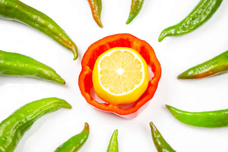 red sweet and green hot peppers and lemon on a white background. cooking vegetables for foodの写真素材