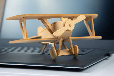 Model of a wooden plane on the background of a laptop. business development and success. Dream to fly in your favorite business.の写真素材