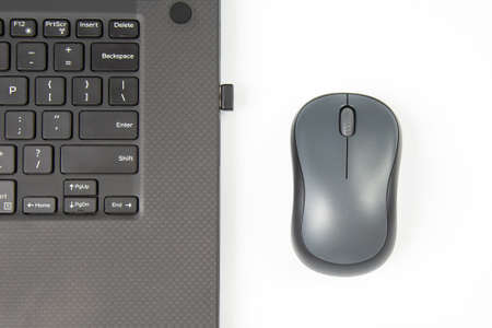 Computer wireless mouse next to a laptop on a white table close-up. electronic personal industry